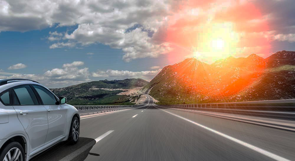 Car on the highway with a red and orange camera flare in the top right